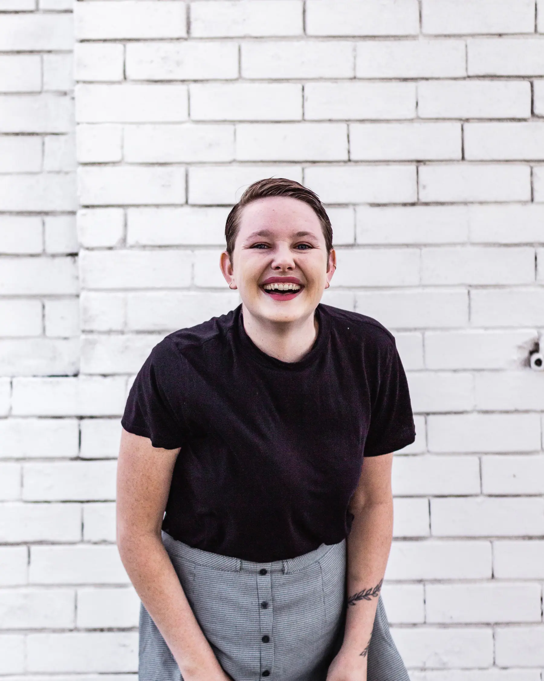 A young woman smiling on a white wall background