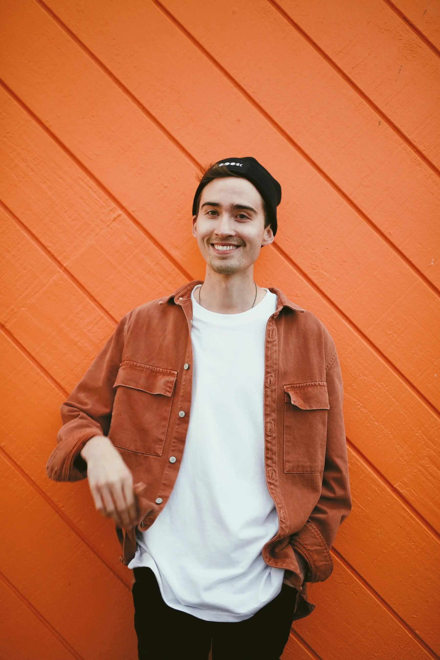 A young man smiling on an orange background